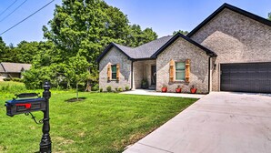 A two-story house with a stone facade, a garage, and a well-maintained lawn. - New Everything! Comfy Home w/ Deck & Trail Access! (Bella Vista)