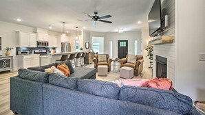 A modern living room with a grey sectional sofa, a fireplace, and a kitchen in the background. - New Everything! Comfy Home w/ Deck & Trail Access! (Bella Vista)