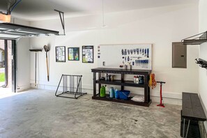 Un garage avec un mur équipé d’un panneau perforé, un établi et divers outils.