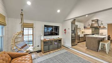A modern living room with a leather sofa, a wooden entertainment unit, and a large flat-screen TV.