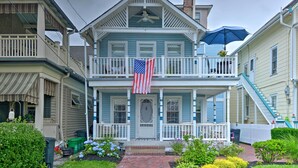 Ein zweistöckiges Haus mit Balkon, einer amerikanischen Flagge und einer Veranda.