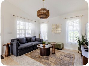 Een moderne woonkamer met een hoekbank, een rond bijzettafeltje en een hanglamp.