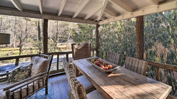 Un espace extérieur aménagé, abrité et doté de meubles en osier et d’une table en bois sur laquelle se trouve un panier de fruits.