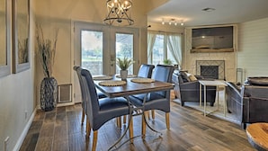 A dining area with a wooden table and chairs, a chandelier, and a fireplace in the background. - Modern Townhome w/ Patio, Next Door to Resort (Horseshoe Bay)