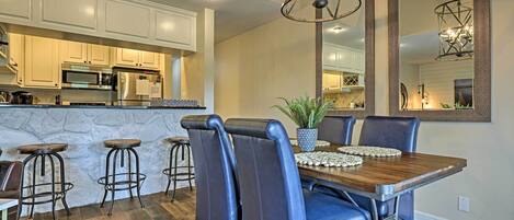 A dining area with a wooden table, blue chairs, and a potted plant.