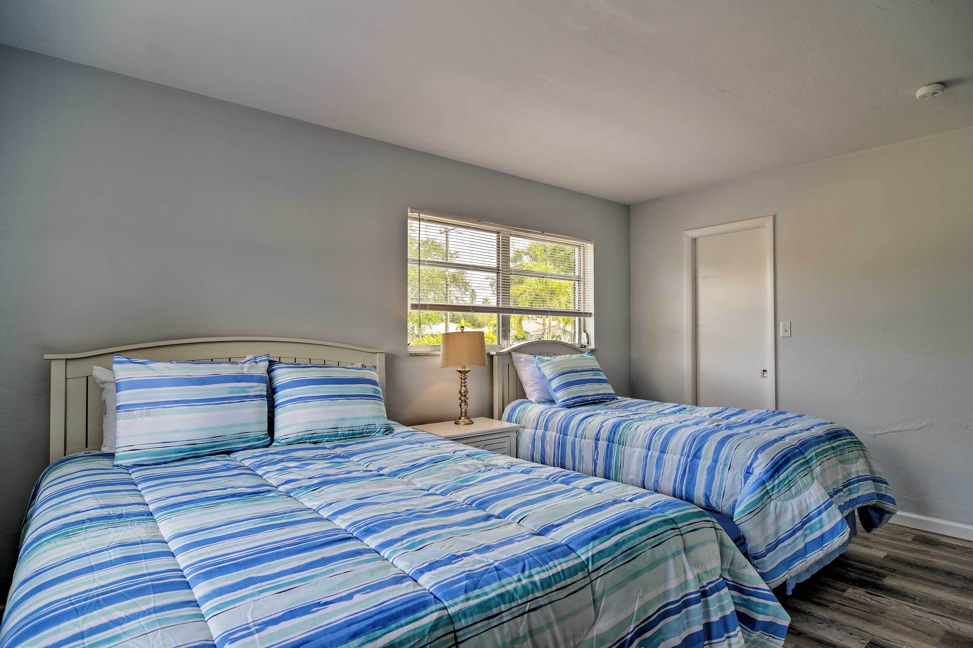 A bedroom with two beds, a window, and a door.