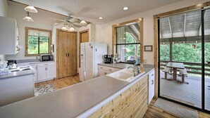 Une cuisine moderne avec des meubles en bois, un grand îlot central et une vue sur une terrasse extérieure.