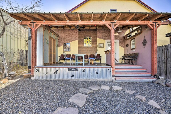 Un espace extérieur aménagé, abrité et doté de chaises et de tables, ainsi qu’une pergola en bois et un chemin de gravier menant à l’entrée.