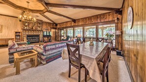 A cozy log cabin interior with a fireplace, wooden furniture, and large windows. - House of Angels Retreat w/ Deck Near Winter Park (Ruidoso)
