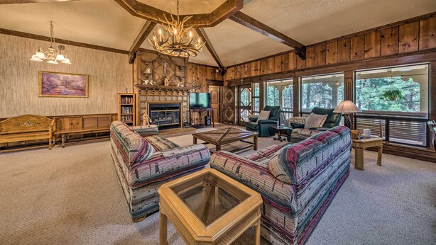 A cozy living room with a fireplace, comfortable seating, and large windows offering a view of the outdoors. - House of Angels Retreat w/ Deck Near Winter Park (Ruidoso)