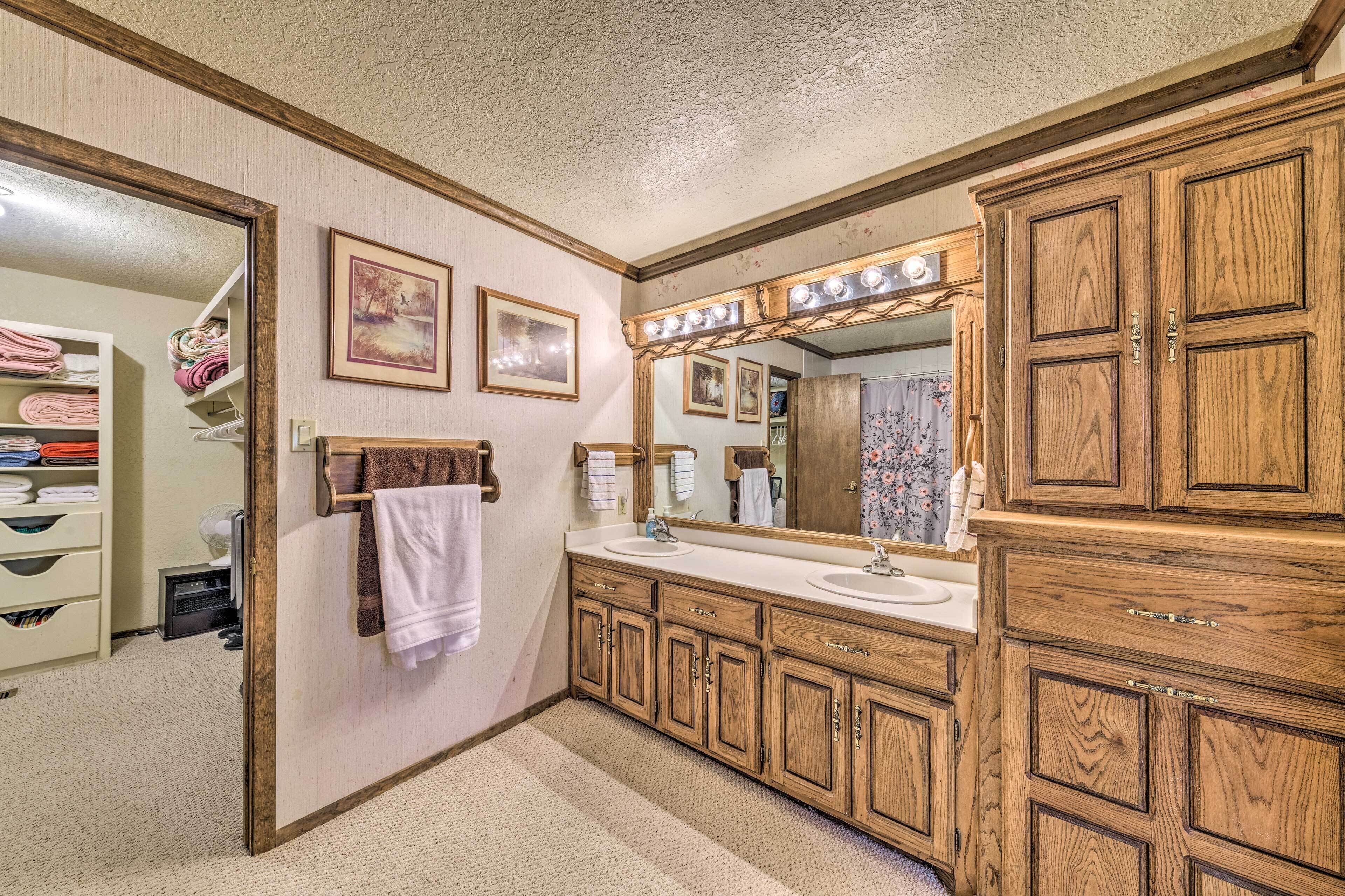 A bathroom with wooden cabinets, a large mirror with lights, and a sink.