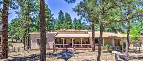 A building with a covered porch, surrounded by trees and a dry landscape.