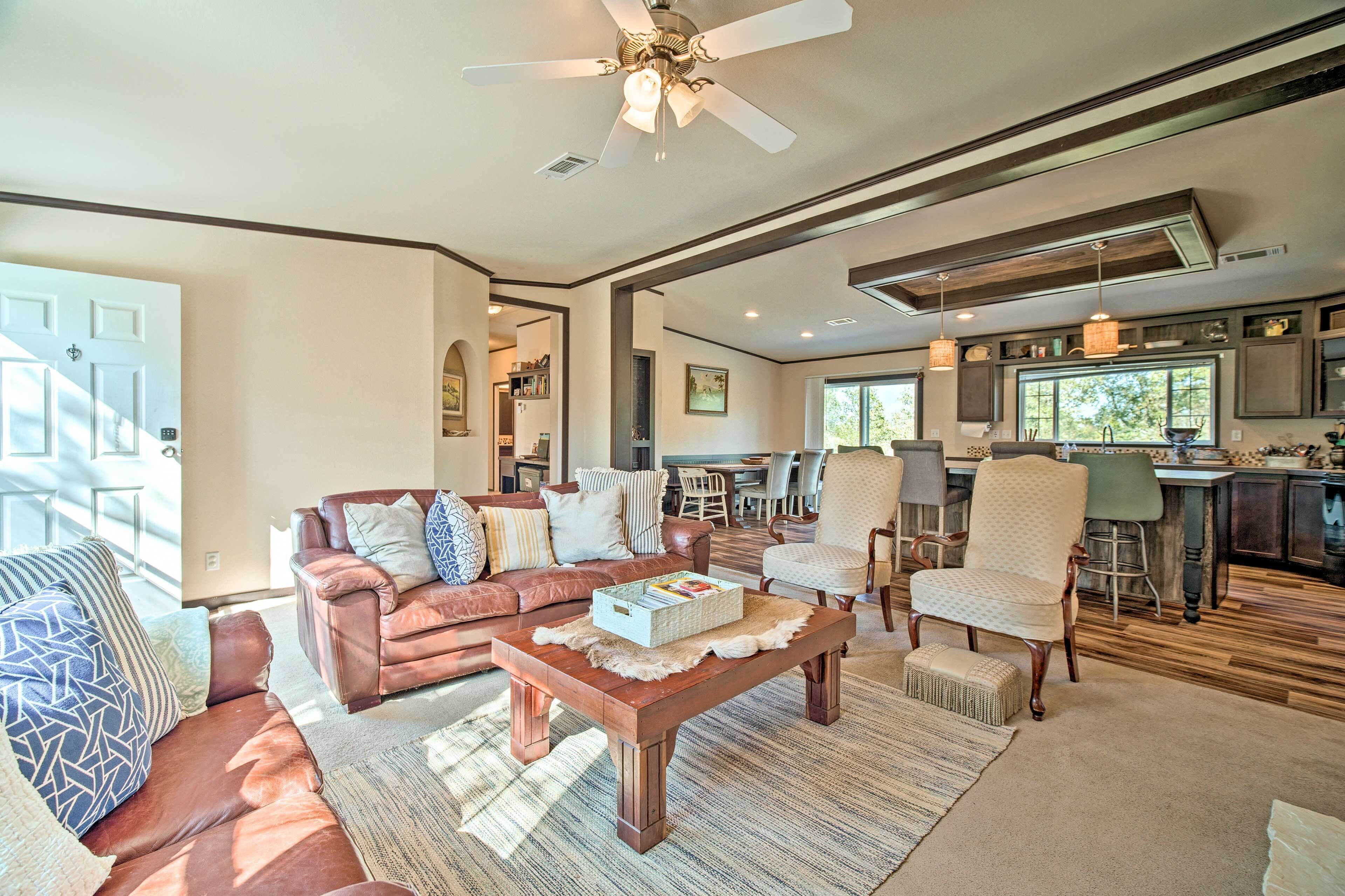 A spacious living area with a brown leather sofa, a wooden coffee table, and a dining area with a bar.