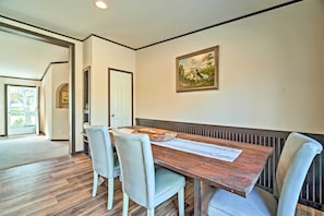 Zona pranzo con tavolo in legno, quattro sedie e un quadro appeso al muro.