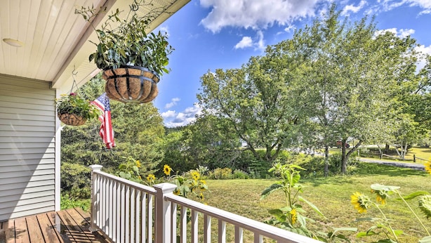 A wooden deck with white railings, hanging planters, and an American flag. - Sunny Morristown Home - Walk to Restaurants! (Morrisville)