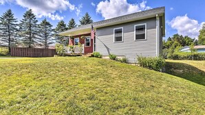 A single-story house with a front porch, a small deck, and a well-maintained lawn. - Sunny Morristown Home - Walk to Restaurants! (Morrisville)