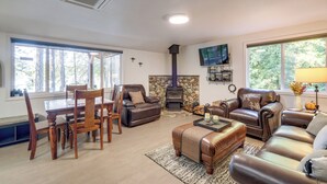 Ein gemütliches Wohnzimmer mit Kamin aus Stein, Ledermöbeln und einem an der Wand befestigten Fernseher.