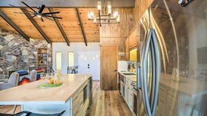 A modern kitchen with a large stainless steel refrigerator, wooden cabinets, and a stone accent wall. - Pine Mountain Cabin w/ Hot Tub, 2 Mins to Marina! (Groveland)