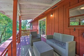 A covered porch with wicker furniture, a wooden railing, and a view of the surrounding greenery. - Dog-friendly Bella Vista Home w/ Grill + Deck (Bella Vista)