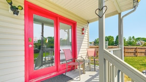 A house with a red door, a porch with chairs, and a wooden fence in the background. - Richmond Area Home w/ Game Room & Patio! (Sandston)