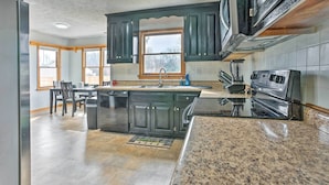 A kitchen with dark cabinets, a granite countertop, a built-in oven, and a window above the sink. - Richmond Area Home w/ Game Room & Patio! (Sandston)