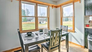 A dining area with a table set for four, large windows, and a view of a backyard. - Richmond Area Home w/ Game Room & Patio! (Sandston)