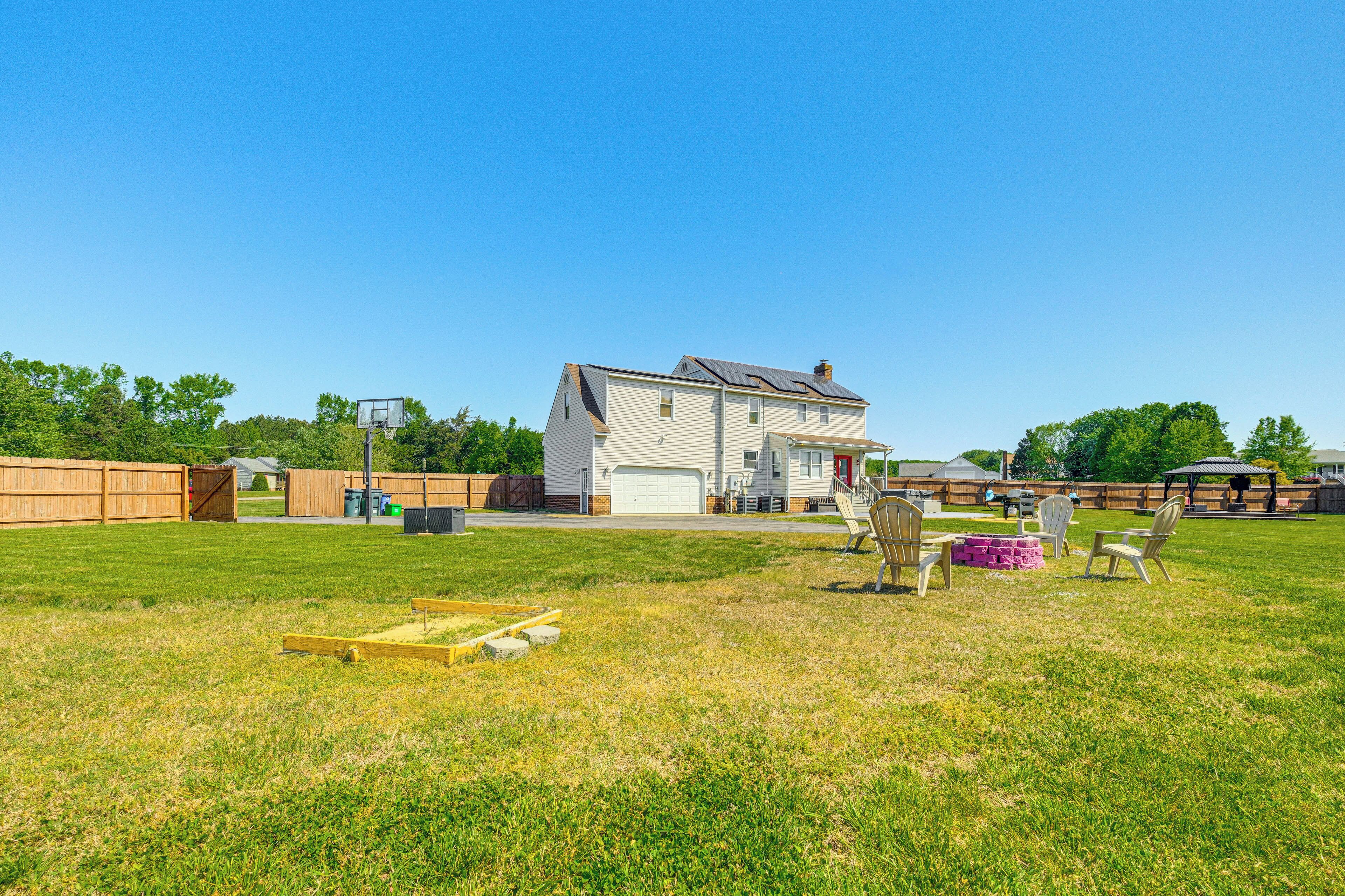 A house with a garage, a backyard with a wooden deck, and a patio area with outdoor furniture.