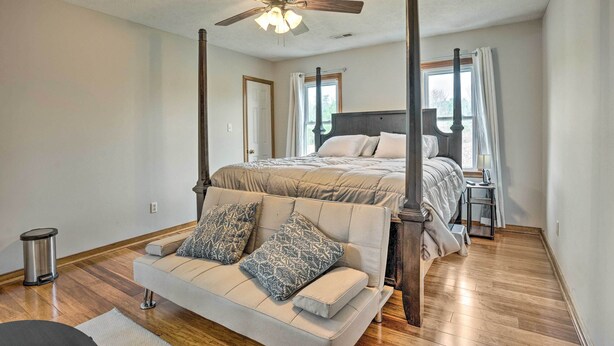 A bedroom with a four-poster bed, a ceiling fan, a window with curtains, and a wooden floor. - Richmond Area Home w/ Game Room & Patio! (Sandston)
