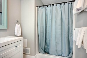 A bathroom with a shower curtain, a sink, and a towel rack.