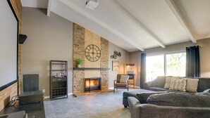 A living room with a fireplace, a sofa, a coffee table, and a TV. - Theater Room & Pool Deck: Retreat in Palm Desert! (Palm Desert)