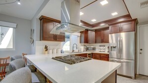 A modern kitchen with a central island, stainless steel appliances, and wooden cabinets. - Theater Room & Pool Deck: Retreat in Palm Desert! (Palm Desert)