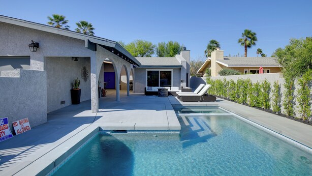 A modern house with a swimming pool, a covered patio, and a view of palm trees. - Theater Room & Pool Deck: Retreat in Palm Desert! (Palm Desert)
