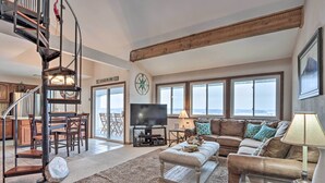 Un salón amplio con escalera, televisor grande y un rincón de estar acogedor.