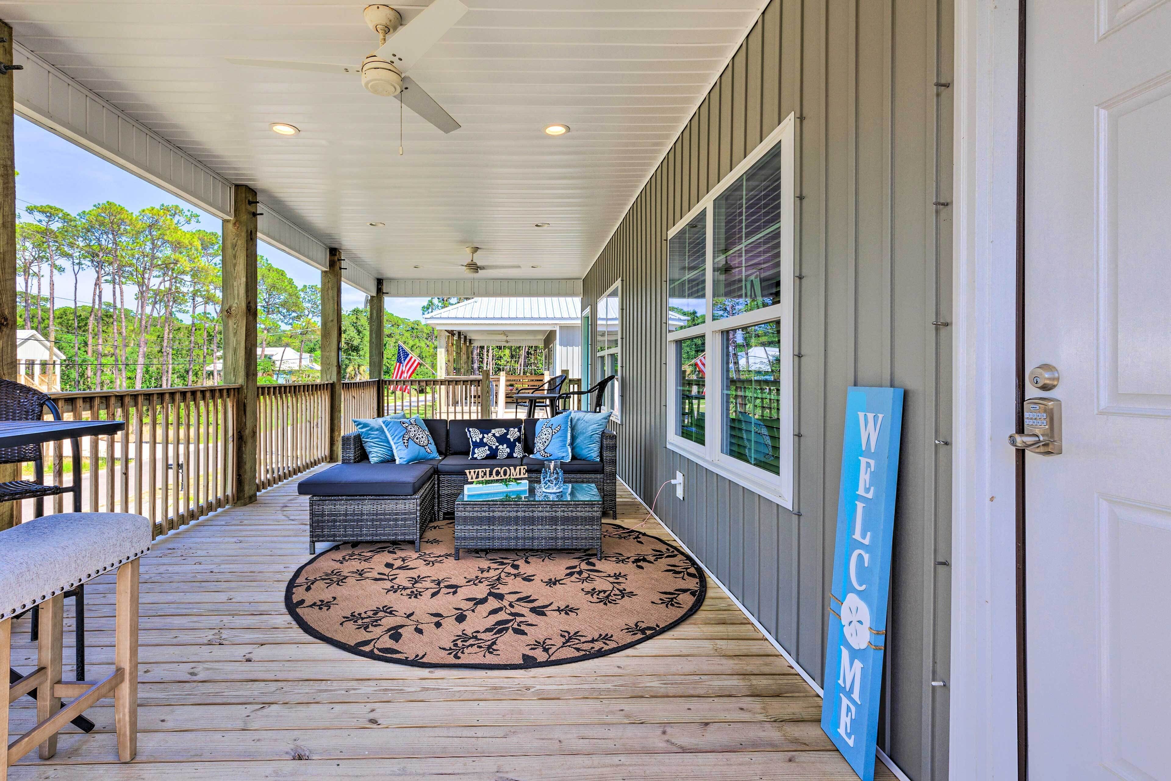A covered porch with a sofa, coffee table, and a welcome sign.
