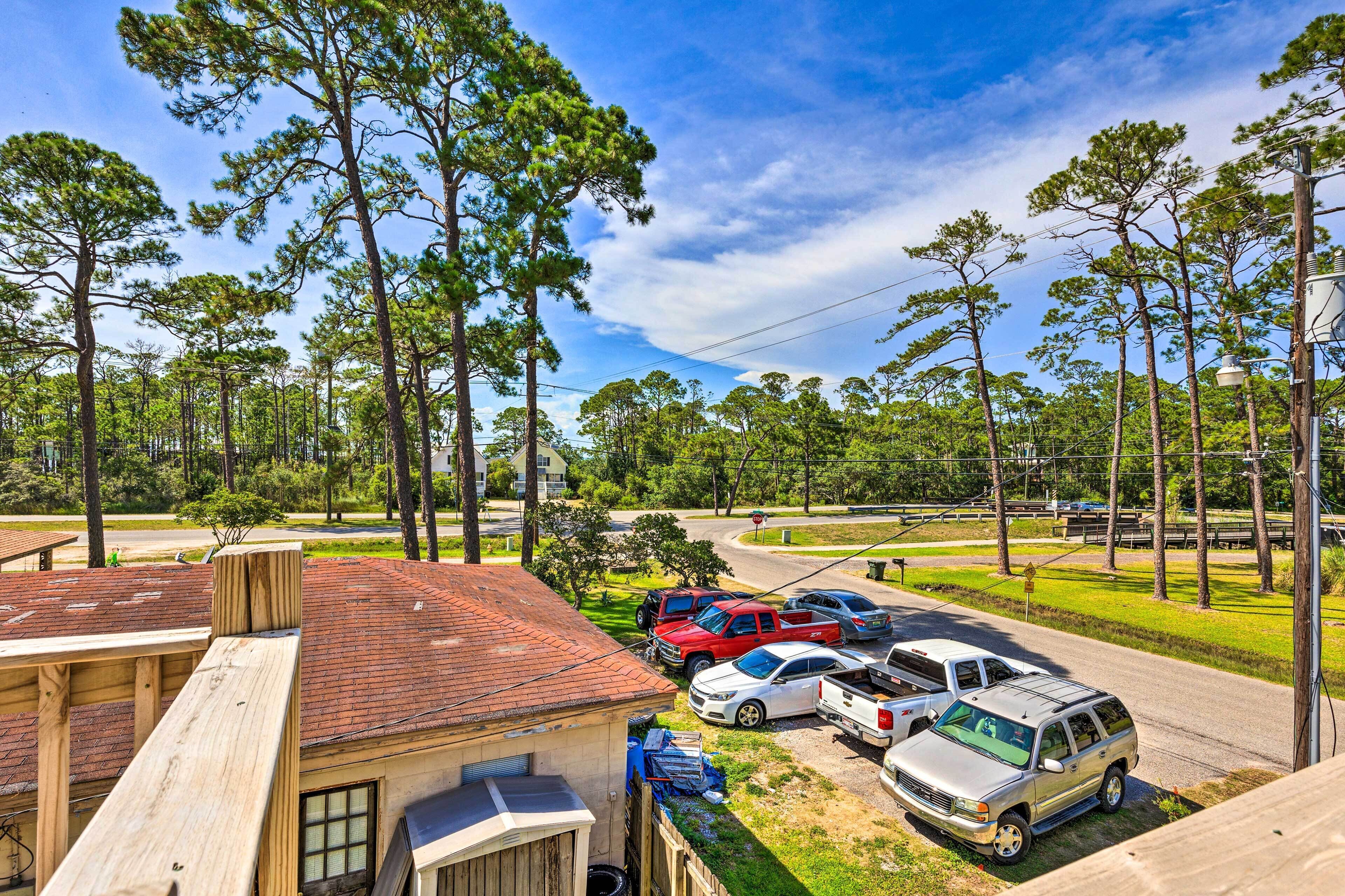 A residential area with a house, parked cars, and a clear sky.