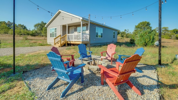 Una casa con porche y patio de grava con sillas Adirondack.