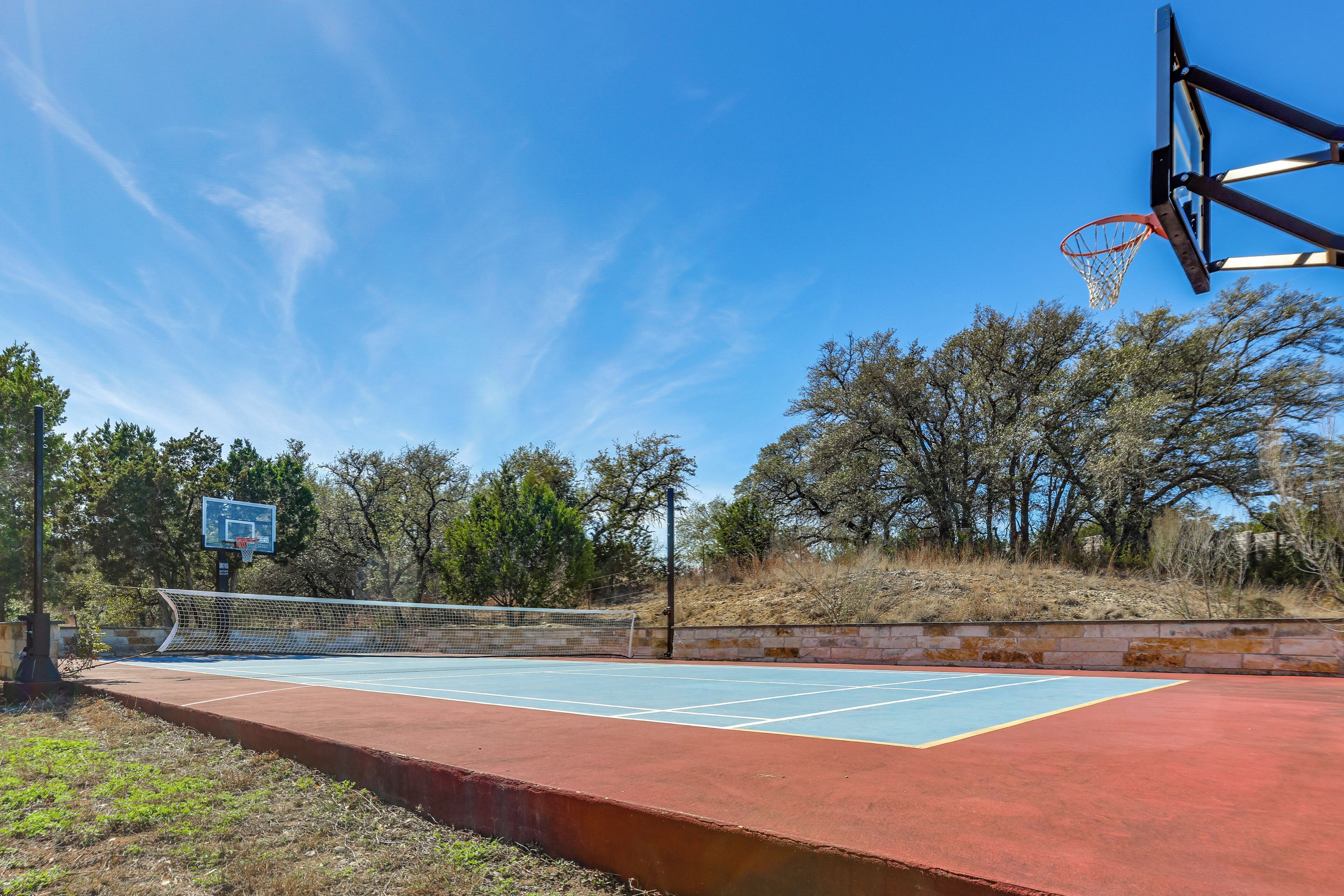 An outdoor basketball court with a blue playing surface, a basketball hoop, and a net.