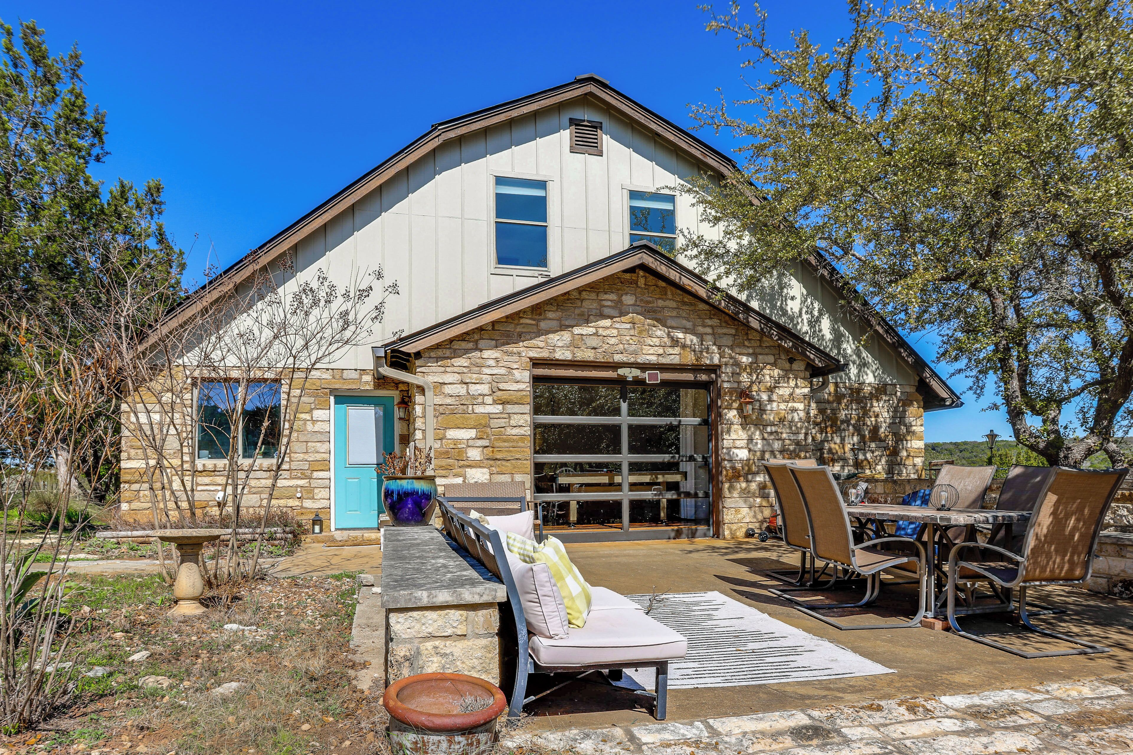 A stone house with a blue door, a patio with a table and chairs, and a stone fireplace.