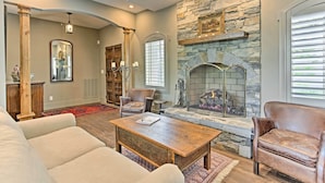 A spacious living room with a stone fireplace, leather sofas, and a wooden coffee table. - Enchanting Tryon Home w/ Hot Tub ~ 14 Mi to Tiec! (Tryon)
