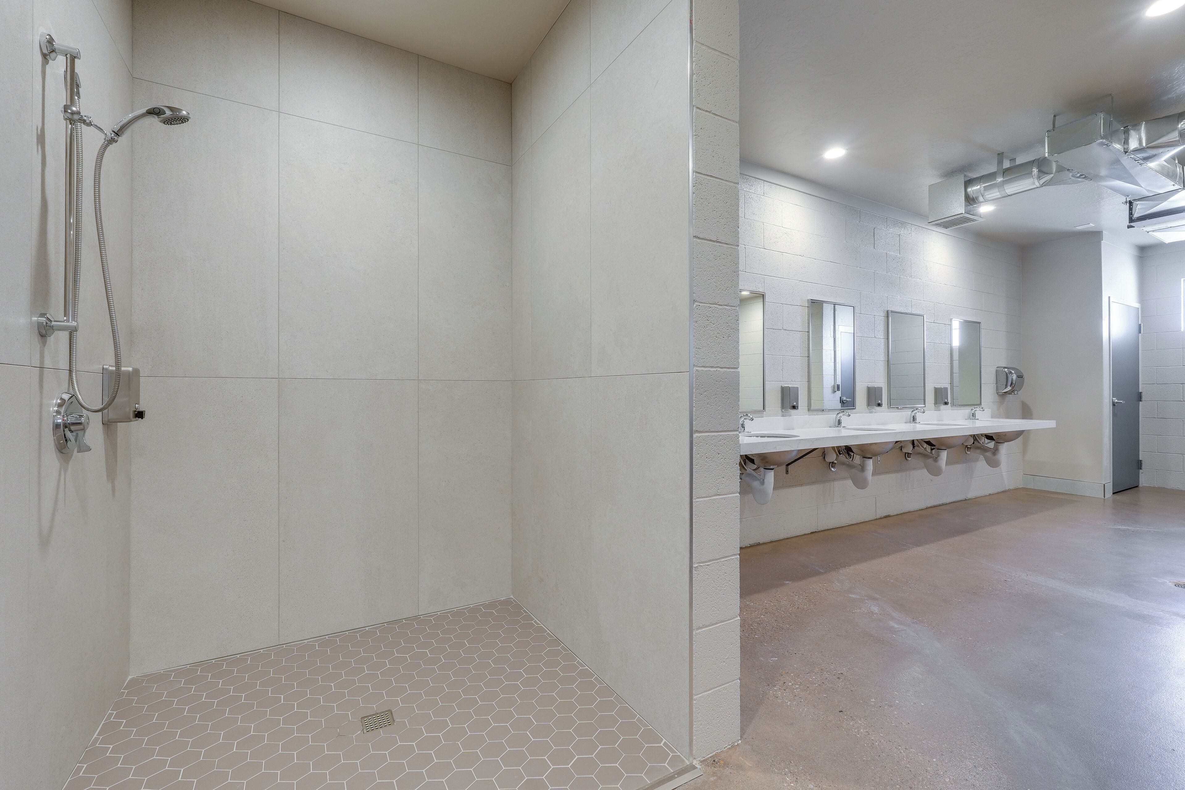 A modern bathroom with a shower, multiple sinks, and a tiled floor.