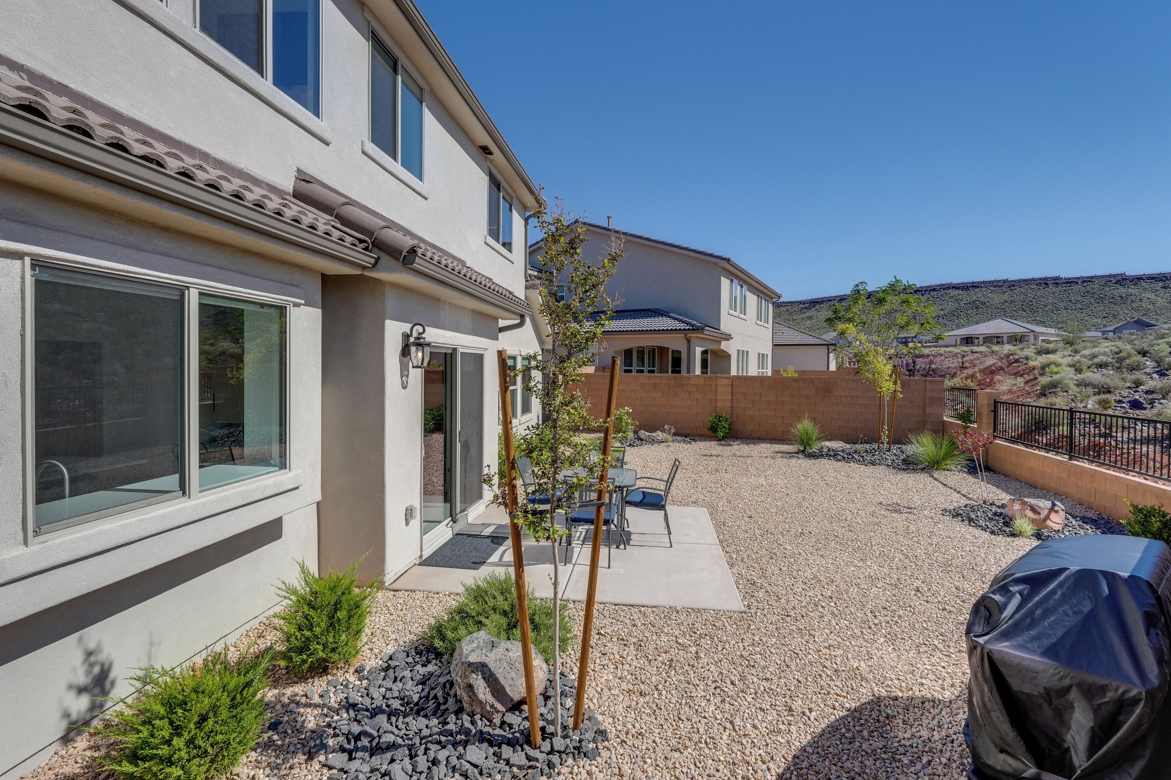 A residential property with a patio, outdoor seating, and a covered grill area.