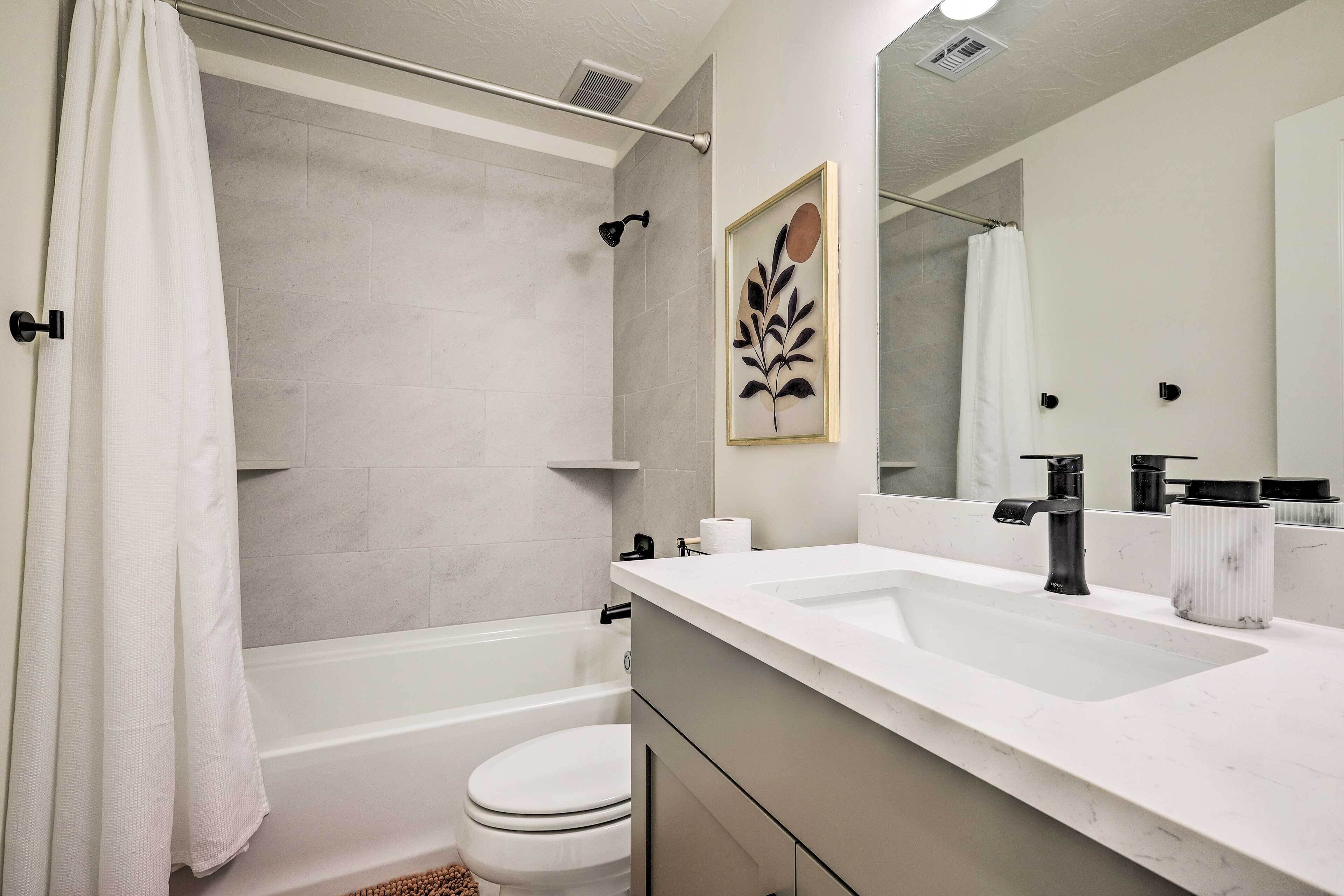A modern bathroom with a bathtub, toilet, and sink.
