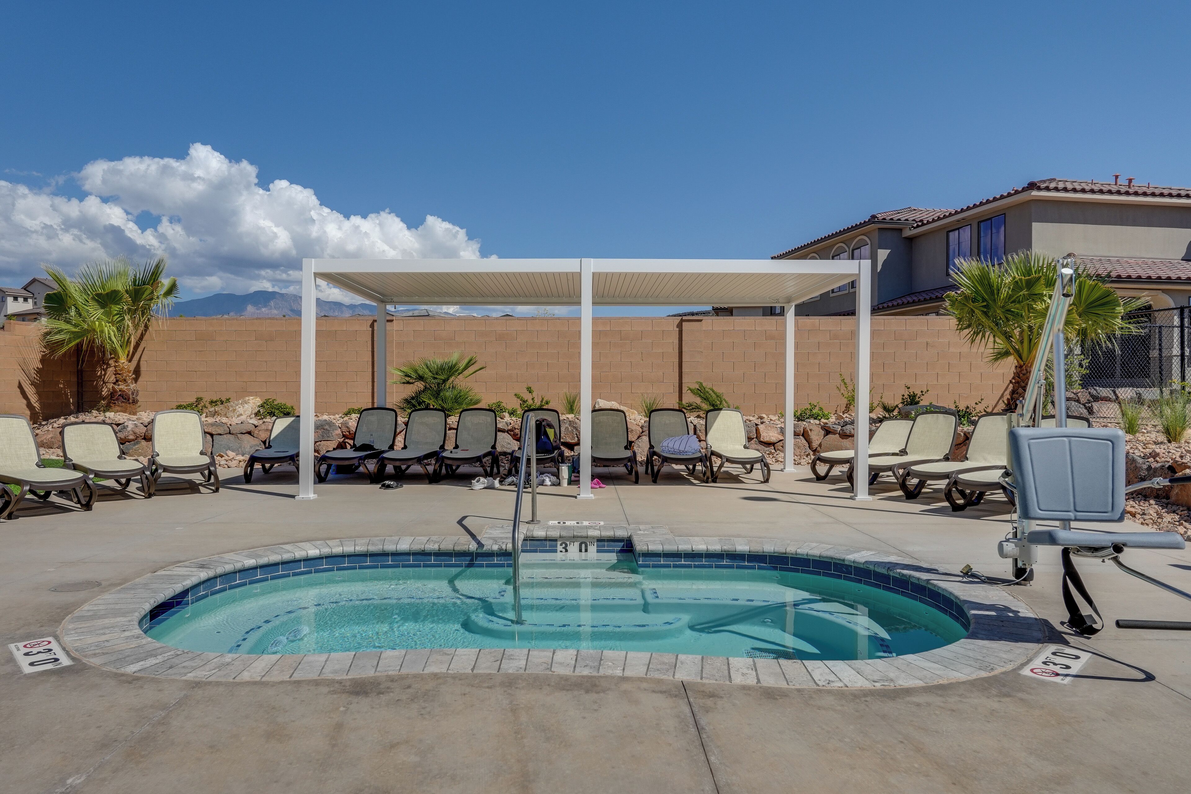 A swimming pool with lounge chairs and a covered seating area.