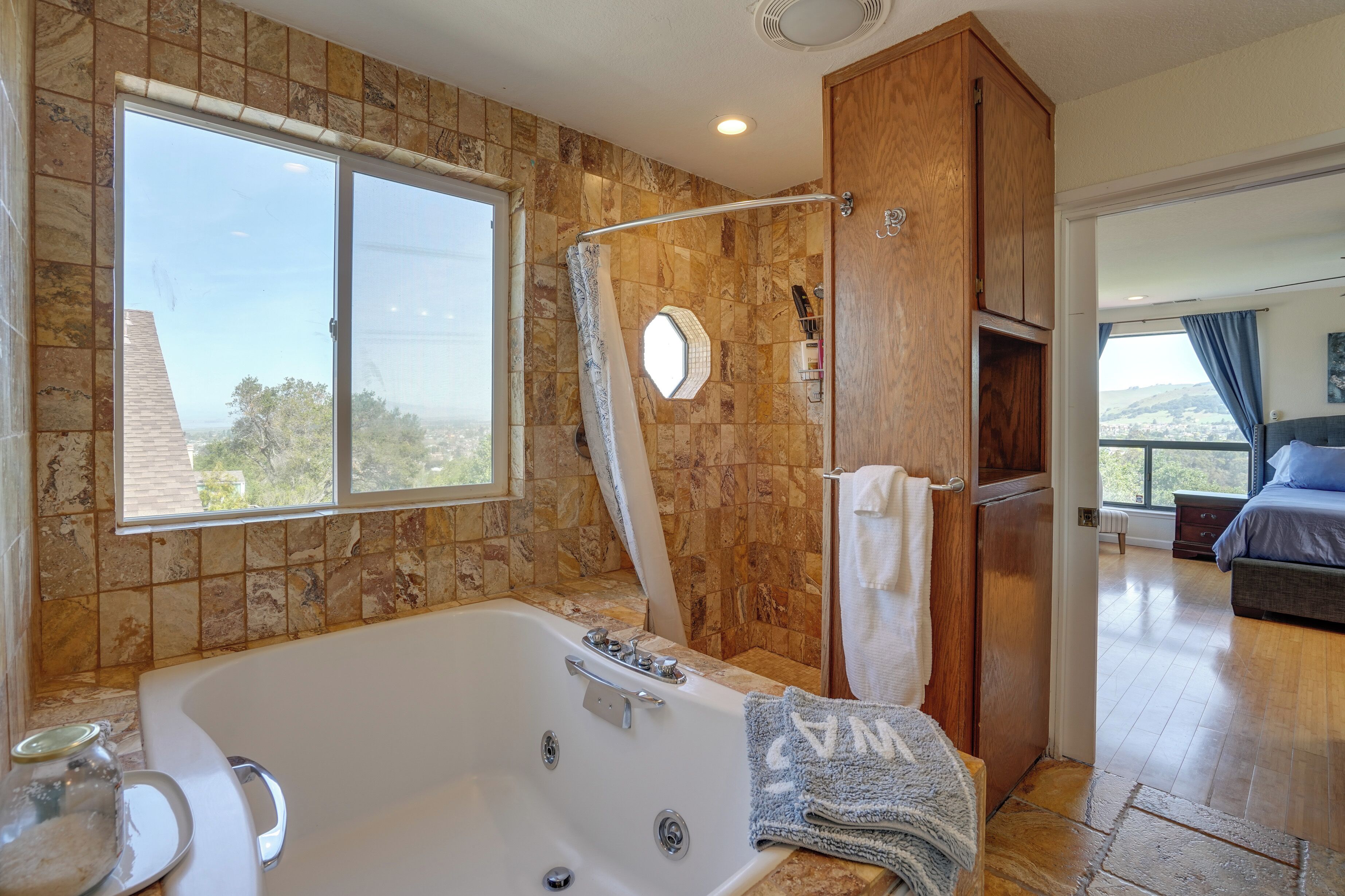 A modern bathroom with a large bathtub, a shower area, and a window providing a view of the outdoors.