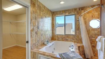 A bathroom with a bathtub, shower, and a window with a view.
