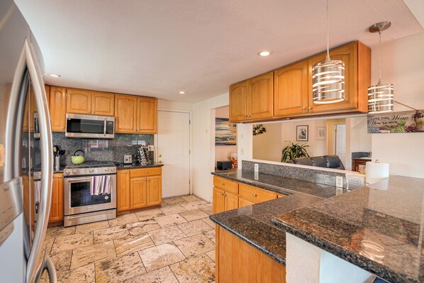 A kitchen with wooden cabinets, stainless steel appliances, granite countertops, and pendant lighting. - Vallejo Home w/ Spacious Deck, Hot Tub & Views (Vallejo)