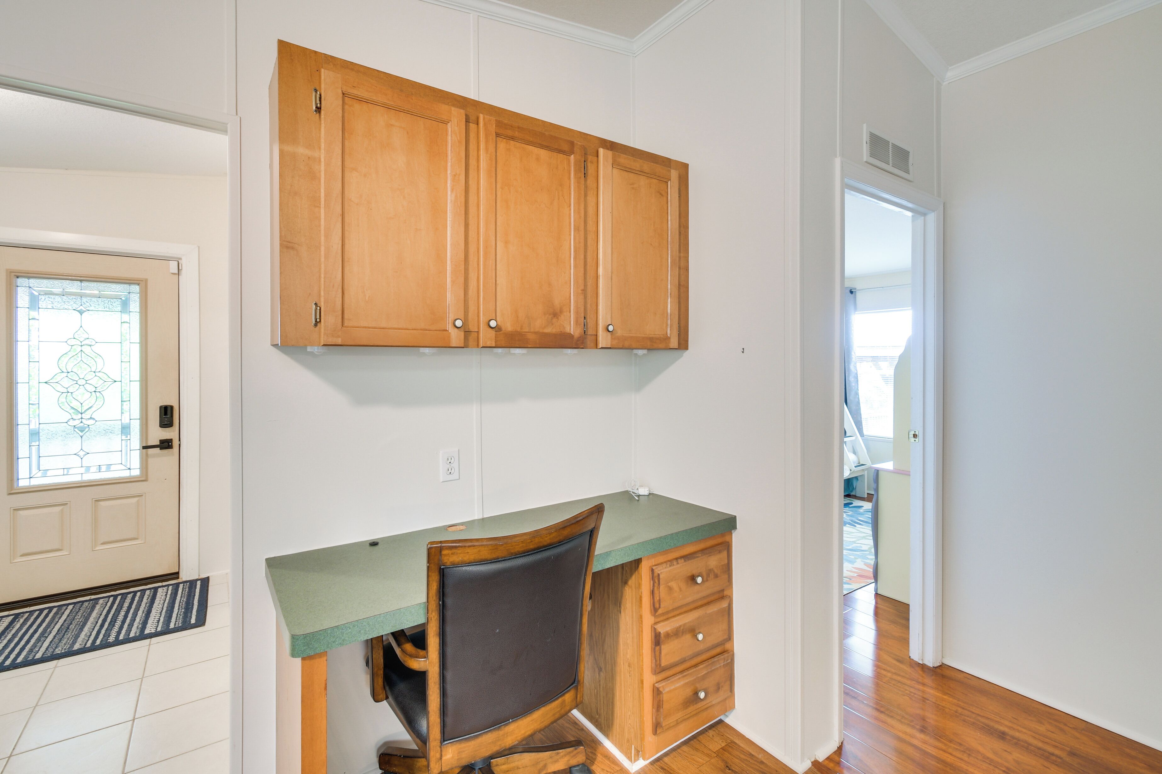 A kitchen with wooden cabinets, a green countertop, and a built-in chair.