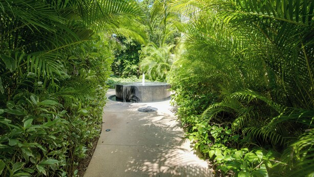 A pathway flanked by lush green foliage leading to a central water feature. - Luxe Tao Riviera Resort Condo w/ Beach & Golfing! (Akumal)