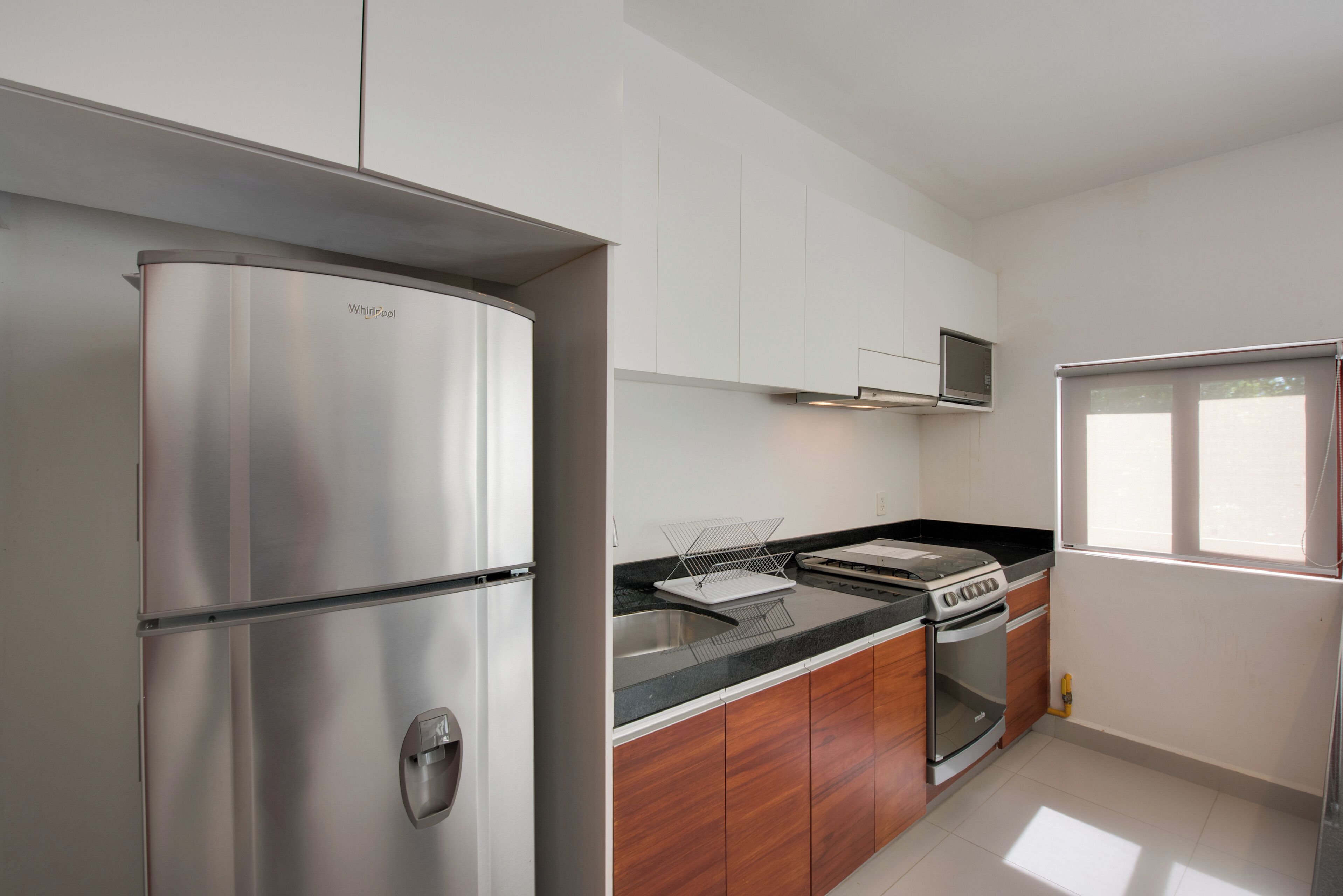 Een moderne keuken met roestvrijstalen apparatuur, houten keukenkastjes en een ingebouwde magnetron.