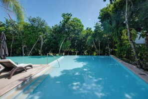 A swimming pool with lounge chairs and a clear view of the surrounding lush greenery.